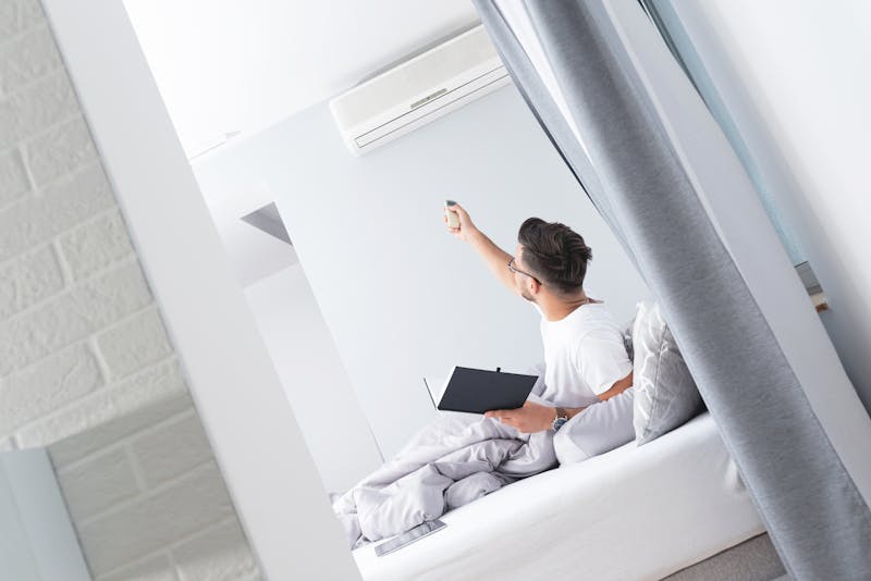 Man bedient airco vanuit bed