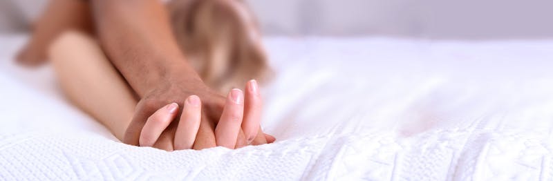 Man en vrouw in bed met verstrengelde handen