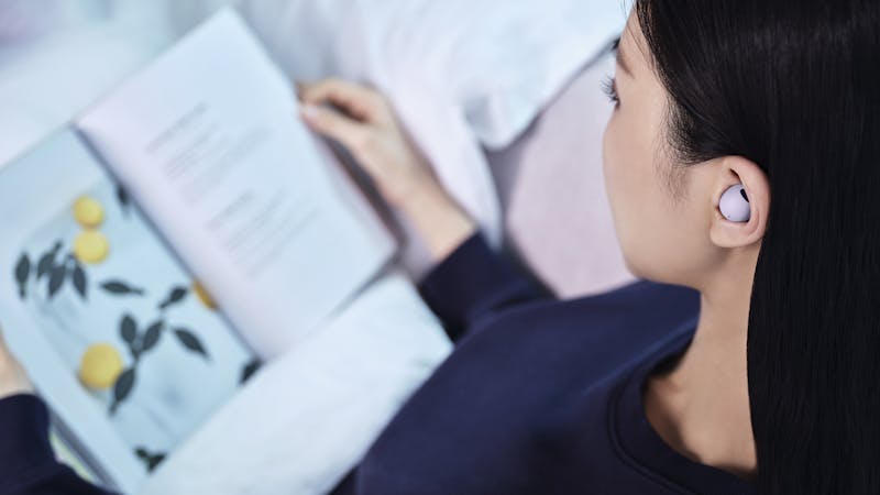 Vrouw leest boek met Samsung Galaxy Buds Pro 2 in oren.