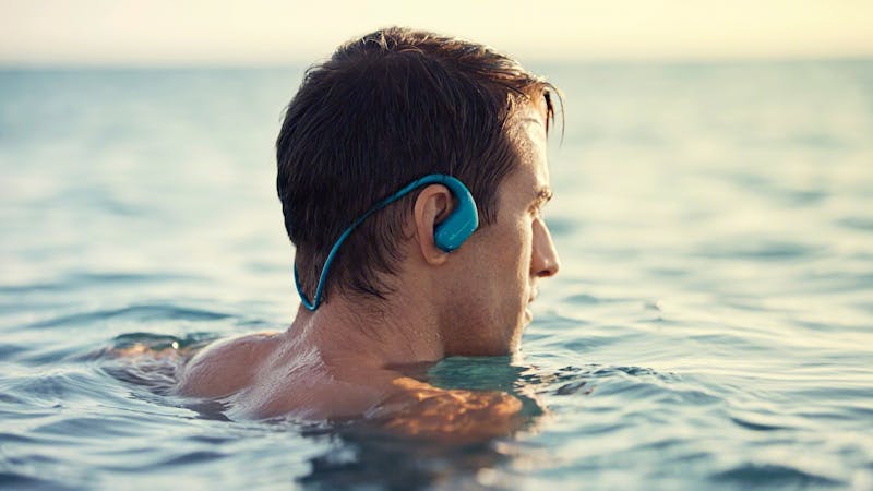 Sony Walkman-sportoordoppen gedragen door een man in de zee.