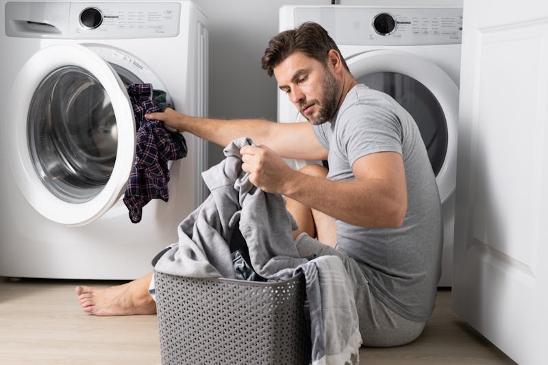 Man sorteert de was bij de wasmachine