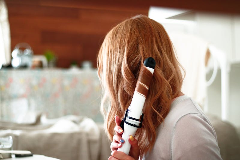 Vrouw krult haar haren met een krultang