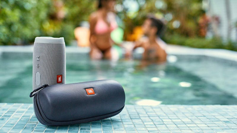 Een waterbestendige Bluetooth-speaker van JBL aan de rand van een zwembad.