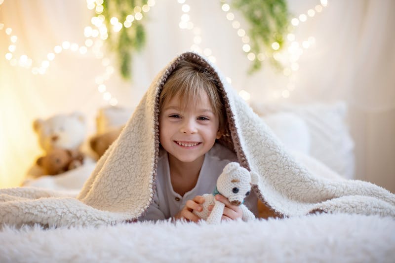 Jongen met teddybeer in bed