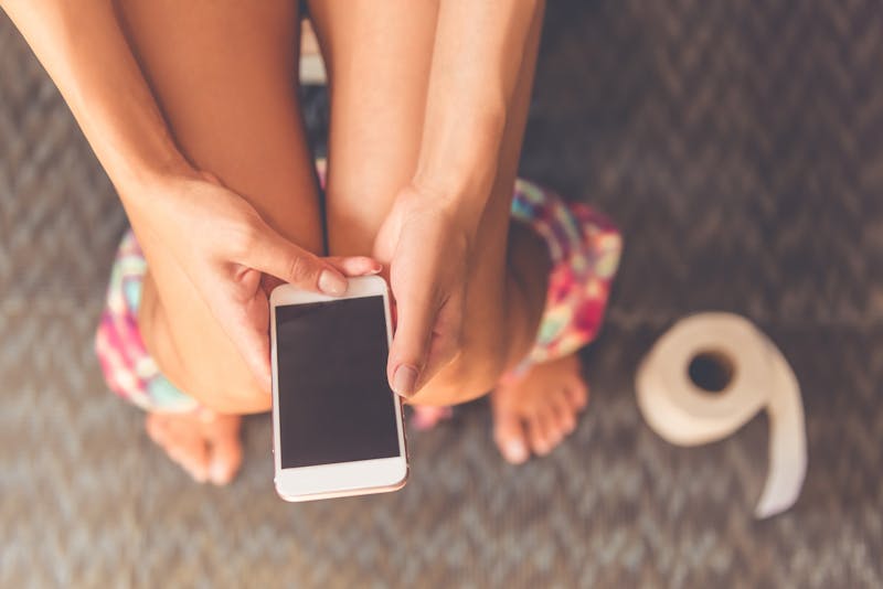 Vrouw met telefoon op de wc