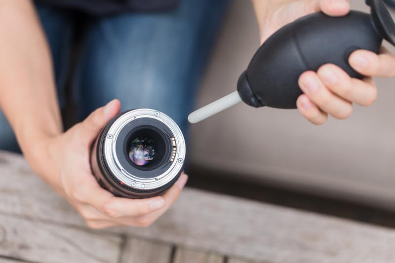 objectief van camera schoonmaken met blaasbalg