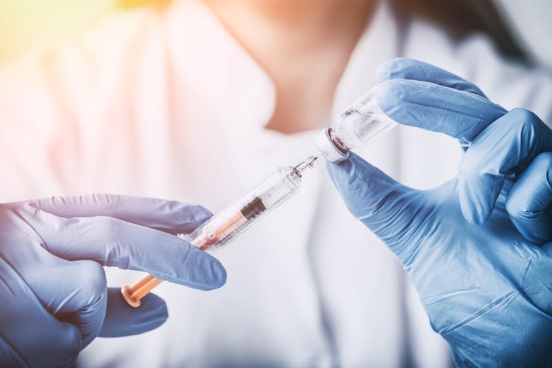 Vrouw vult injectienaald met vaccinatievloeistof