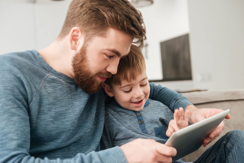 Een vader en zoon kijken samen op een tablet