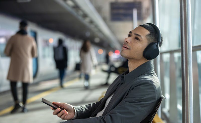 Man luistert naar muziek via koptelefoon in een station.