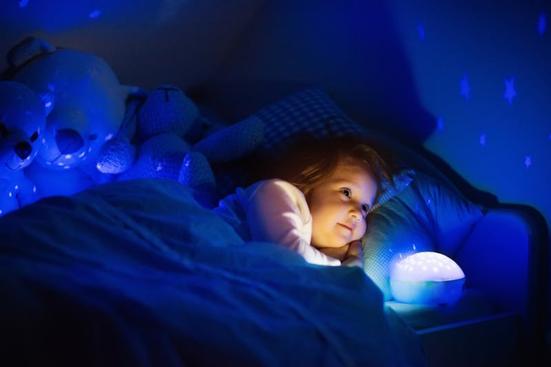 Meisje met nachtlamp in bed