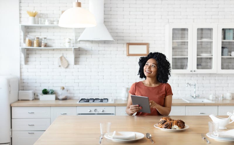 Vrouw met tablet in een witte keuken