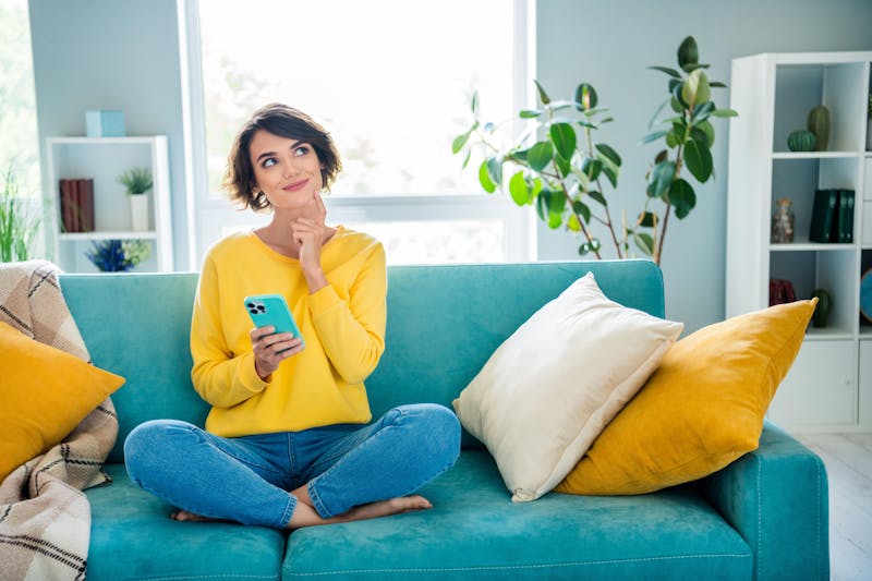 vrouw die zit op de bank met telefoon