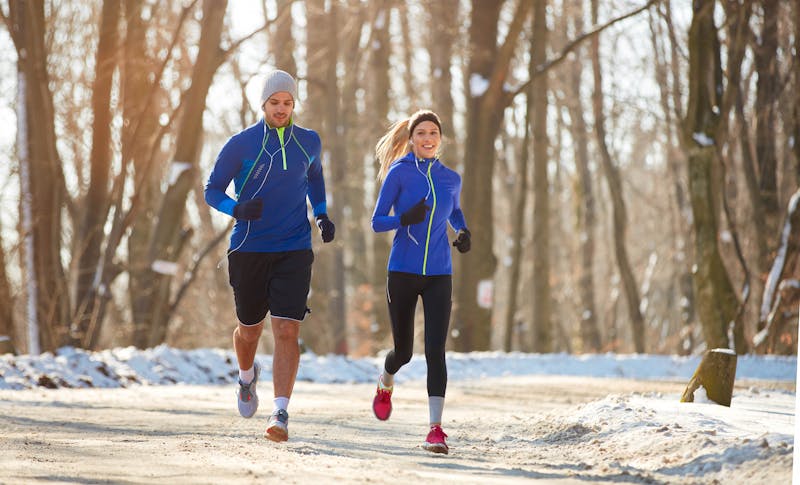 Man en vrouw die hardlopen in de sneeuw