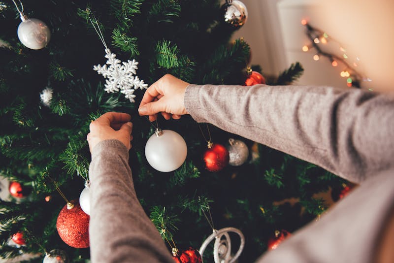 Vrouw die een kerstboom versiert.