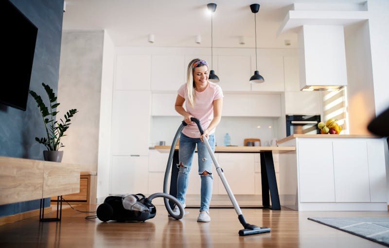 Vrouw is lachend aan het stofzuigen met zakloze stofzuiger