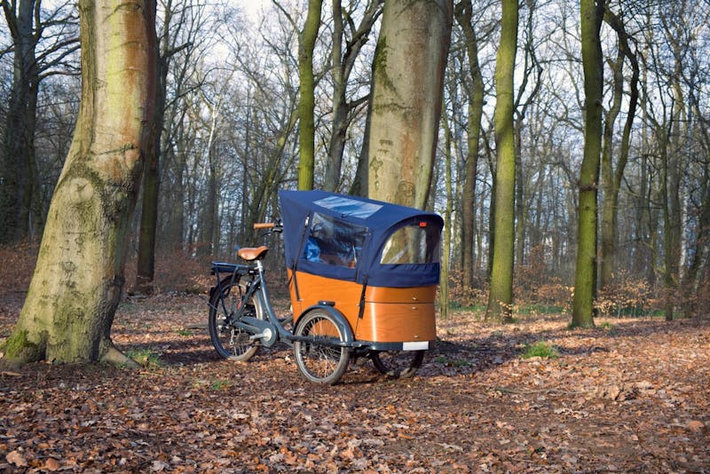 Een bakfiets met een regenhoes over de bak