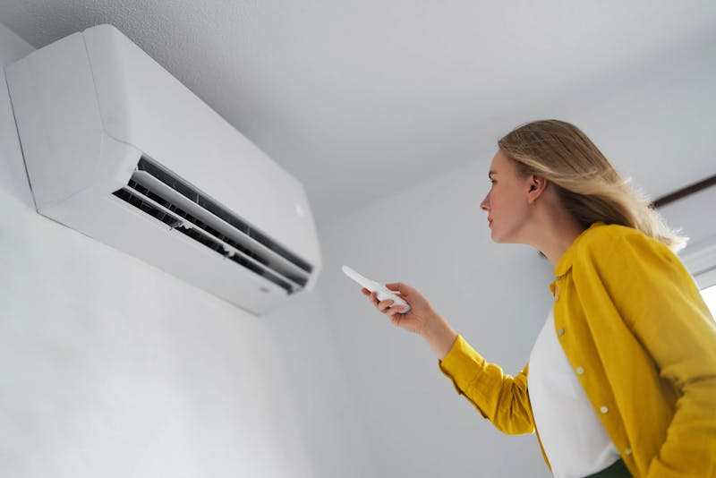 Vrouw die met afstandsbediening airco bedient