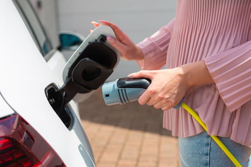 Vrouw sluit laadkabel aan op de auto