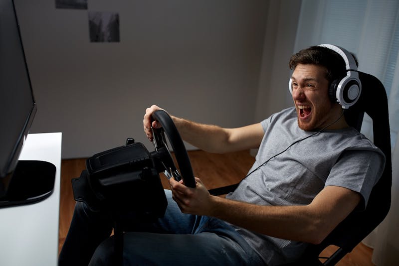 Man speelt racespel met stuur en pedalen