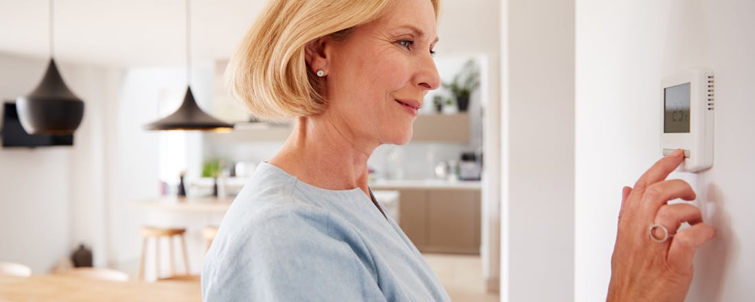 vrouw past thermostaat aan Video: De beste slimme thermostaat om kosten te besparen