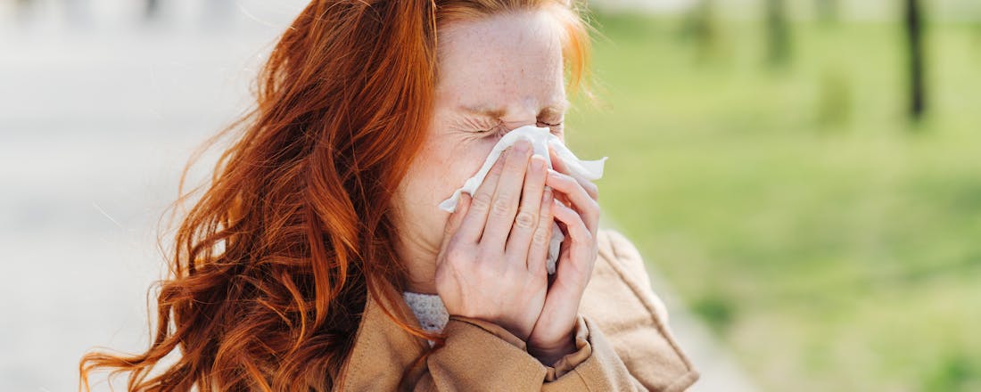 Vrouw die niest Is het een verkoudheid, griep of corona?