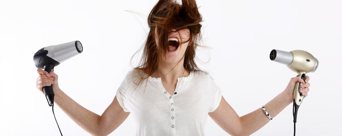 Vrouw met wild haar en twee föhns Je haar föhnen, hoe doe je dat eigenlijk?
