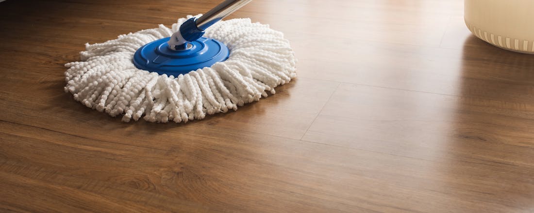 Iemand dweilt een houten vloer Van houten vloer en pvc tot laminaat: alle vloeren weer blinkend schoon
