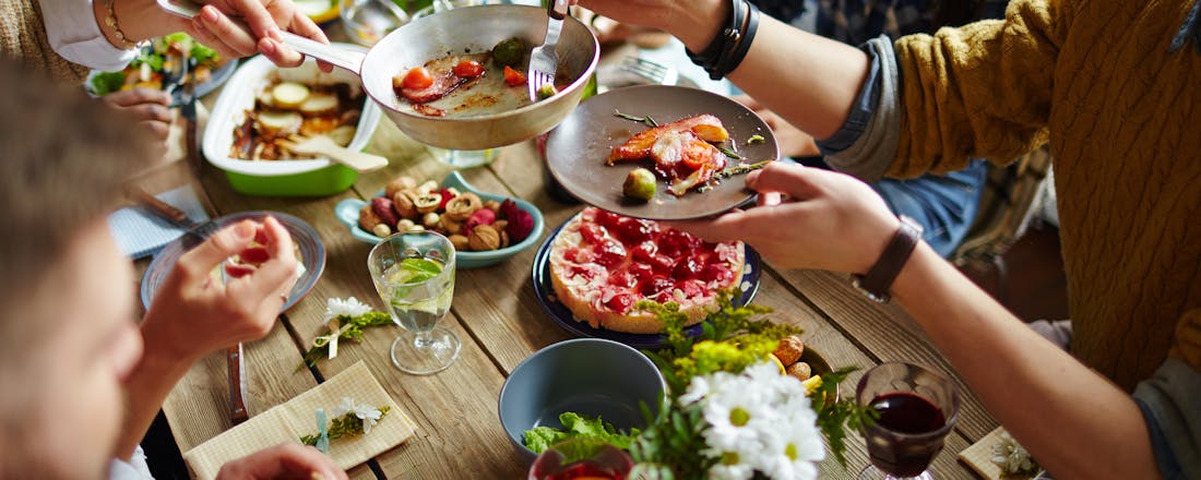 mensen die samen eten Aan tafel! Afvallen en toch lekker koken voor een groot gezelschap