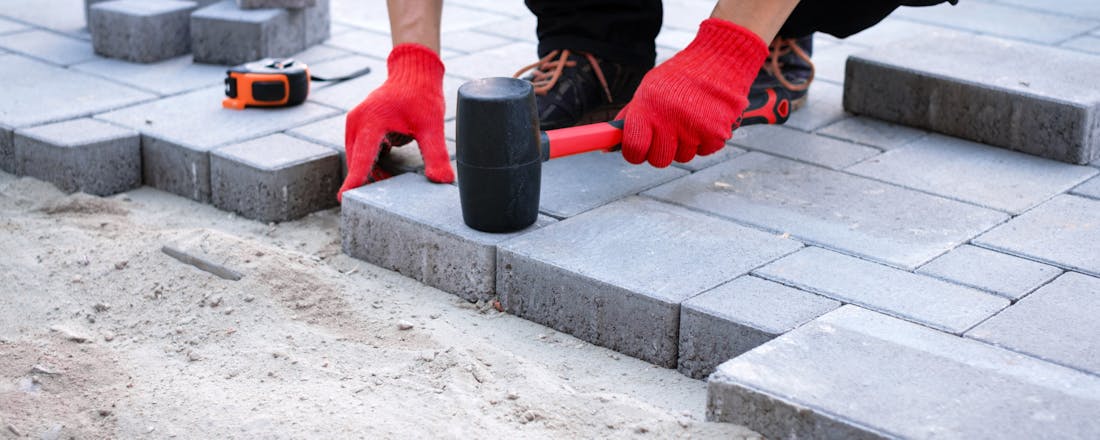 Stratenmaker aan het werk terras bestraten Zelf een terras aanleggen? Dit is waar je op moet letten