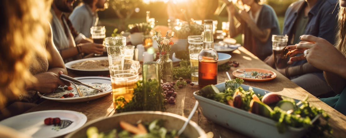 Groep mensen die buiten aan het eten is Proef de zomer: dit zijn de leukste manieren om gezellig buiten te eten