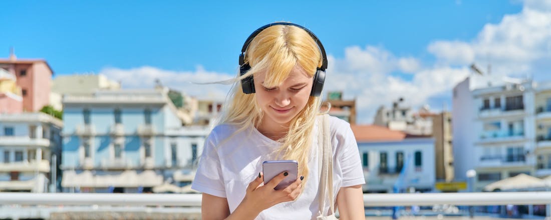 Meisje zit aan het water met smartphone in de hand Smartphone gestolen in het buitenland: 10 tips