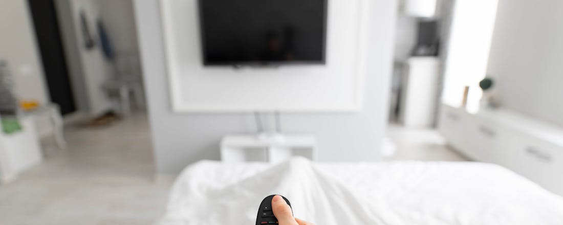 Man met afstandsbediening in bed Waar voor je geld: 5 betaalbare televisies voor een kleine kamer