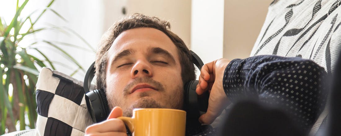Man met koptelefoon en koffie Waar voor je geld: 5 koptelefoons met een accutijd van minstens 50(!) uur