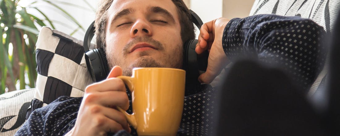 Man met koptelefoon en koffie Waar voor je geld: 5 draadloze over-ear-hoofdtelefoons van max 120 euro