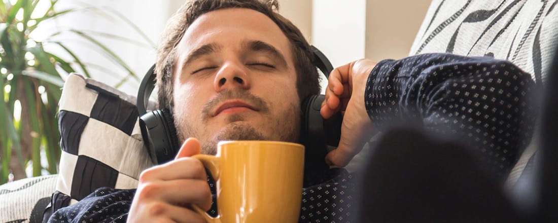 Man met koptelefoon en koffie Zo bepaal je de juiste pasvorm voor je koptelefoon