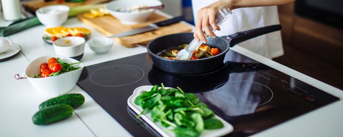 Vrouw kookt op inductie Zo kook je extra zuinig op een inductiekookplaat