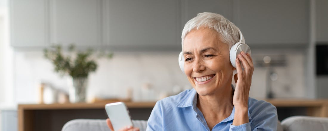Oudere dame luistert naar muziek met koptelefoon en smartphone Zo gebruik je je Android-telefoon als hoortoestel