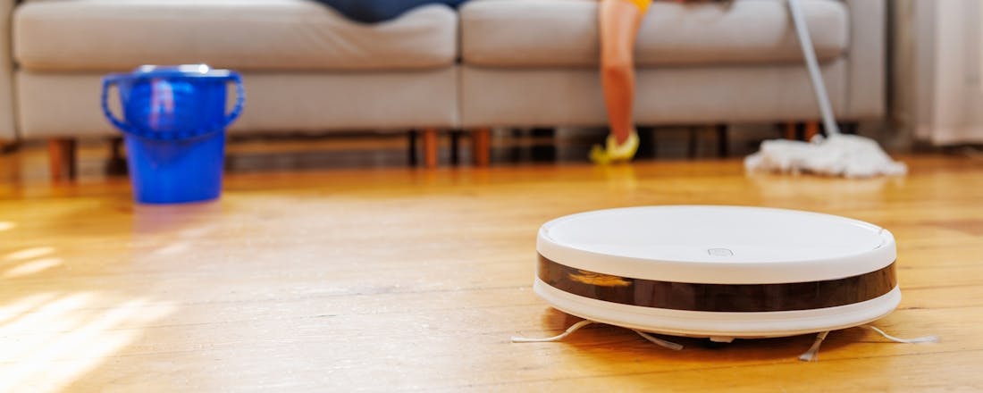 Vrouw ligt op de bank terwijl de robotzuiger het werk doet Waar voor je geld: 5 robotstofzuigers van max 360 euro