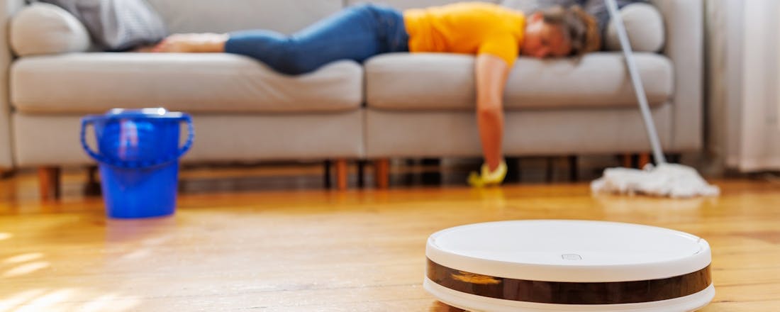 Vrouw ligt op de bank terwijl de robotzuiger het werk doet Stofzuigen zonder moeite: 5 tips om alles uit je robotstofzuiger te halen