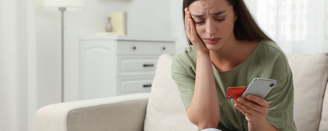 Vrouw die ongerust naar bankpas en smartphone kijkt Vreemd telefoontje van de bank? Bij ING check je nu zelf of het oplichters zijn of niet