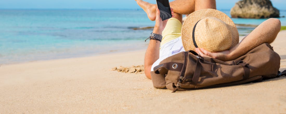 Op vakantie aan het strand Minimaliseer je stroomverbruik thuis als je op vakantie gaat: zo doe je dat!