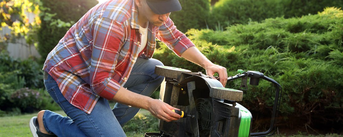 Man die sleutelt aan grasmaaier Van elektrisch tot benzine: zo houd je grasmaaier in topconditie
