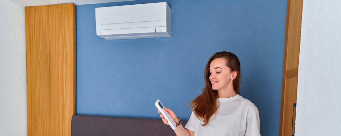 Vrouw bedient airco op de slaapkamer Airco op je slaapkamer: lekker koel in bed!