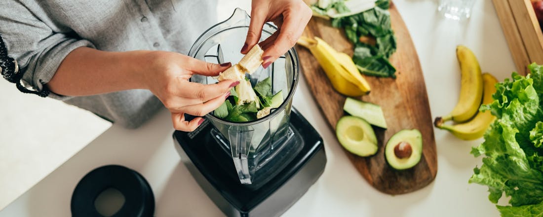 Vrouw maakt smoothies in een blender 5 dingen die je beter niet in de blender kunt stoppen